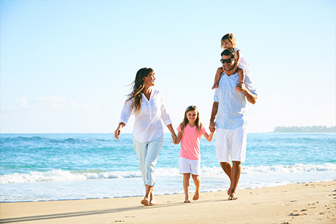 A family walking holding hands walking along the beach